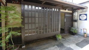 A traditional Japanese-style entrance with a sliding door, a small potted plant, and a sign indicating private residence. - Private Residence Shijo-Karasuma (Kyoto)