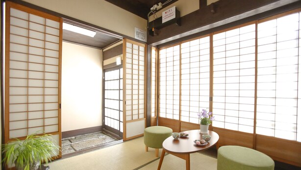 A traditional Japanese room with tatami flooring, a low table with a green cushion, and a potted plant. - Private Residence Shijo-Karasuma (Kyoto)