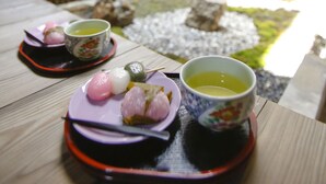 A table with a tea set and traditional sweets, set against a wooden fence and a garden view. - Private Residence Shijo-Karasuma (Kyoto)