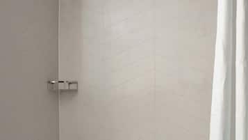 A modern bathroom with a bathtub, shower, and a towel rack.