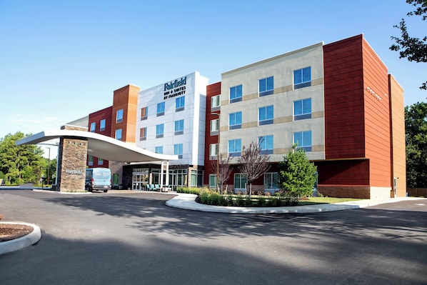 Un hôtel Fairfield Inn & Suites de la chaîne Marriott, doté d’un design moderne, avec un auvent incurvé à l’entrée et un parking.