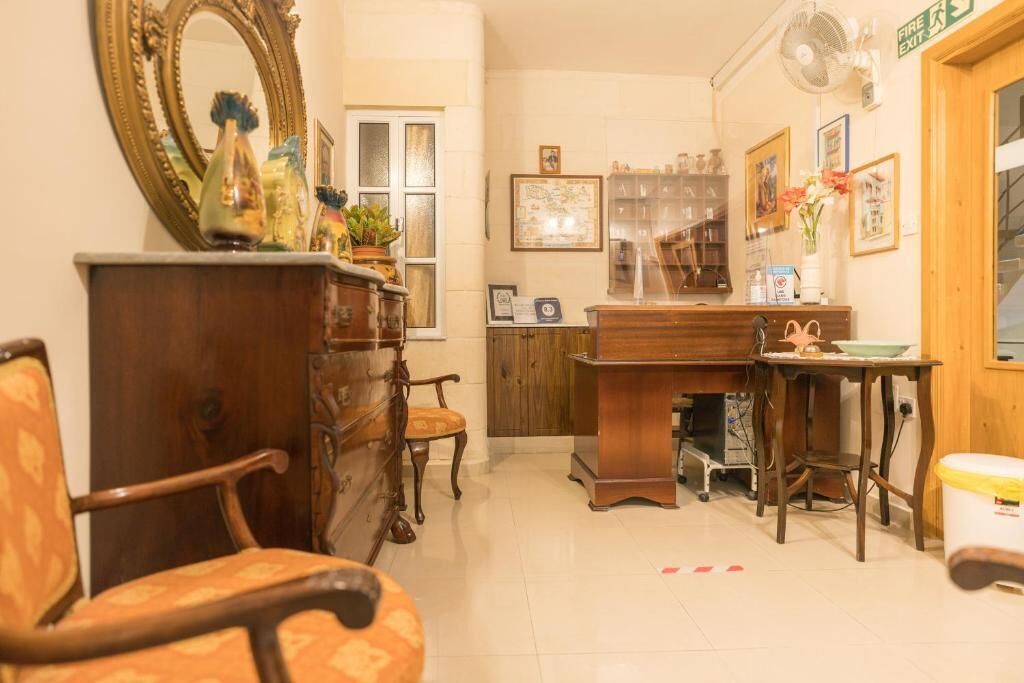 Een kamer met een houten bureau, een stoel, een dressoir, een spiegel en een raam.