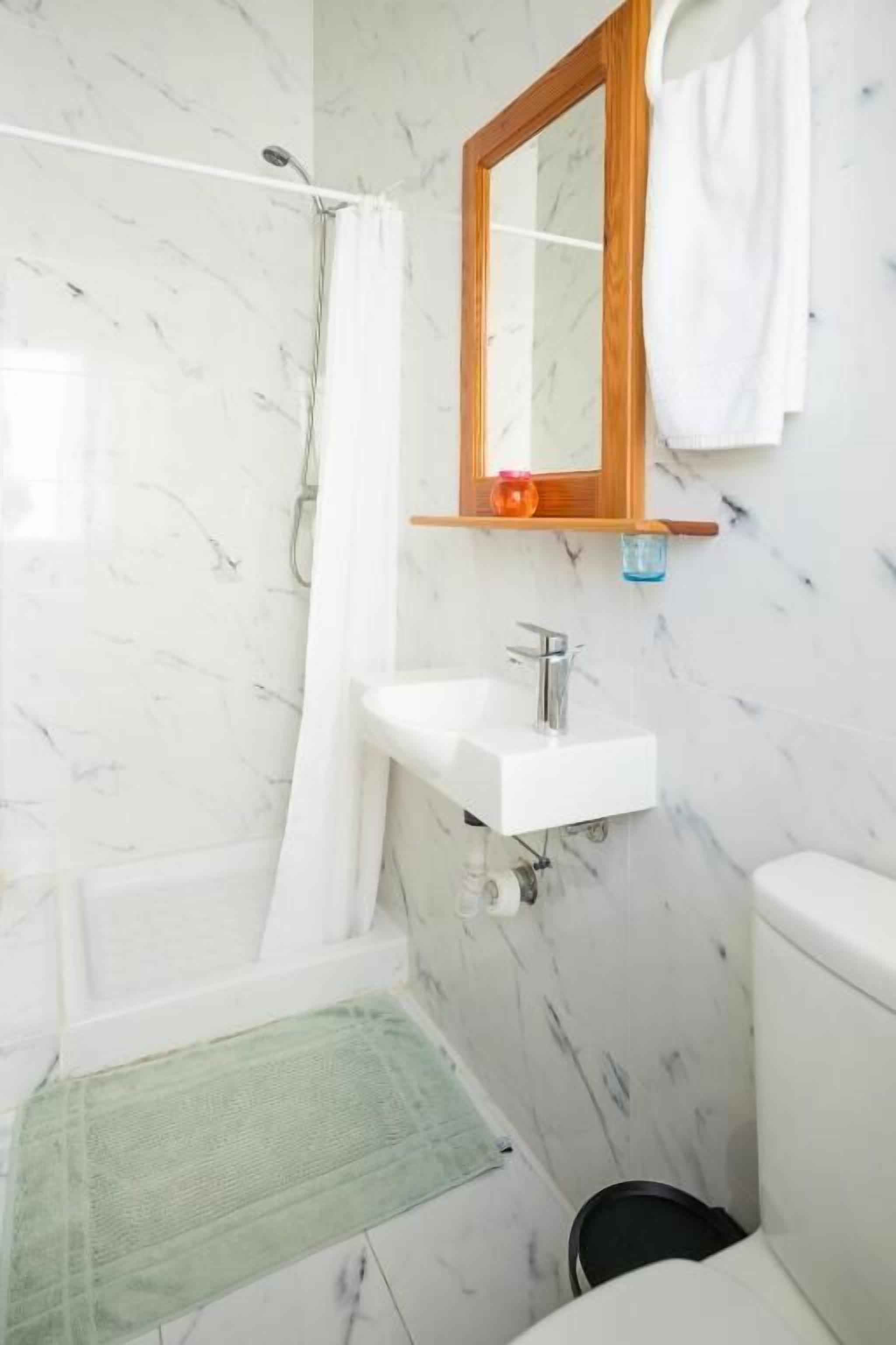 Une salle de bain équipée d’une douche, d’un lavabo, de toilettes et d’un miroir.