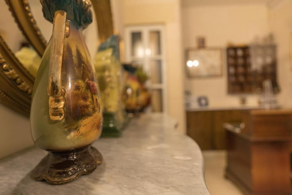 A marble countertop with a decorative glass vase and a mirror.
