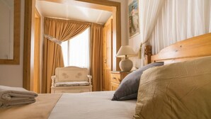A hotel room with a bed, a chair, a nightstand with a lamp, and a painting on the wall. - Lantern Guest House (Zebbug)