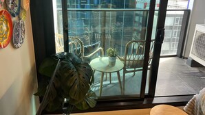 A balcony with a glass door, a potted plant, and a wicker chair.
