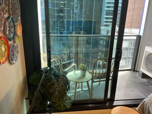 Ein Balkon mit Blick auf ein Gebäude, einem Blumentopf und einem Stuhl.
