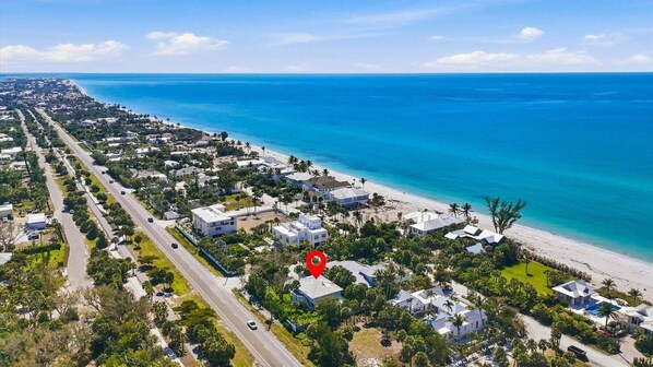 Vista aérea de uma área residencial costeira com praia, ruas e casas.