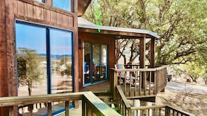 Une cabane en bois dotée d’une terrasse et de grandes fenêtres donnant sur un paysage naturel.