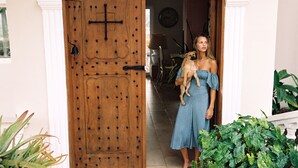 A woman holding a dog in front of a wooden door with a cross symbol. - Private Ocean View Villa - Chef & Staff Included (Puerto Plata)