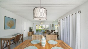 A dining area with a wooden table, wicker chairs, and a central vase.