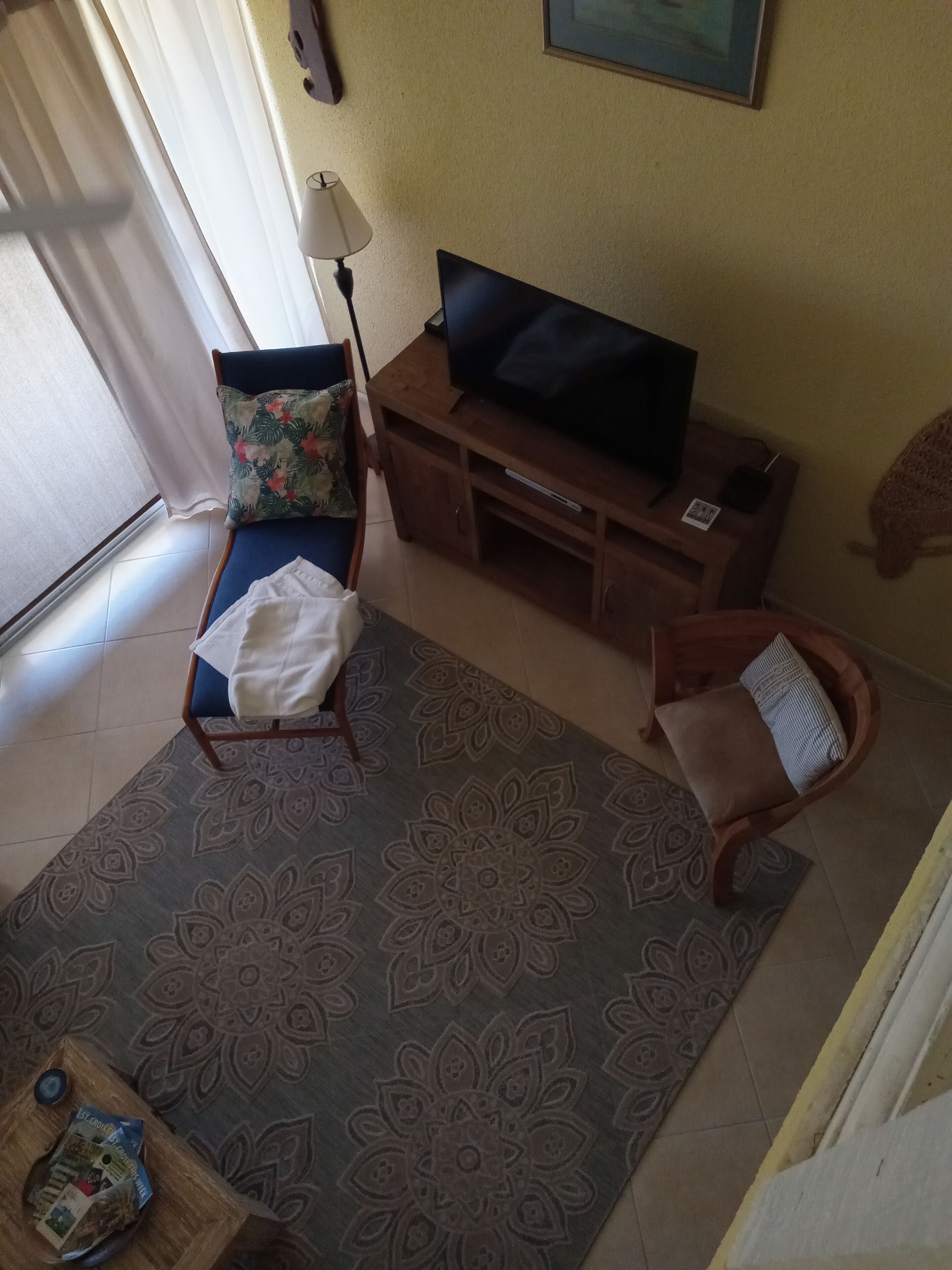 Un salon avec un canapé, un téléviseur, une lampe et un tapis à motifs.