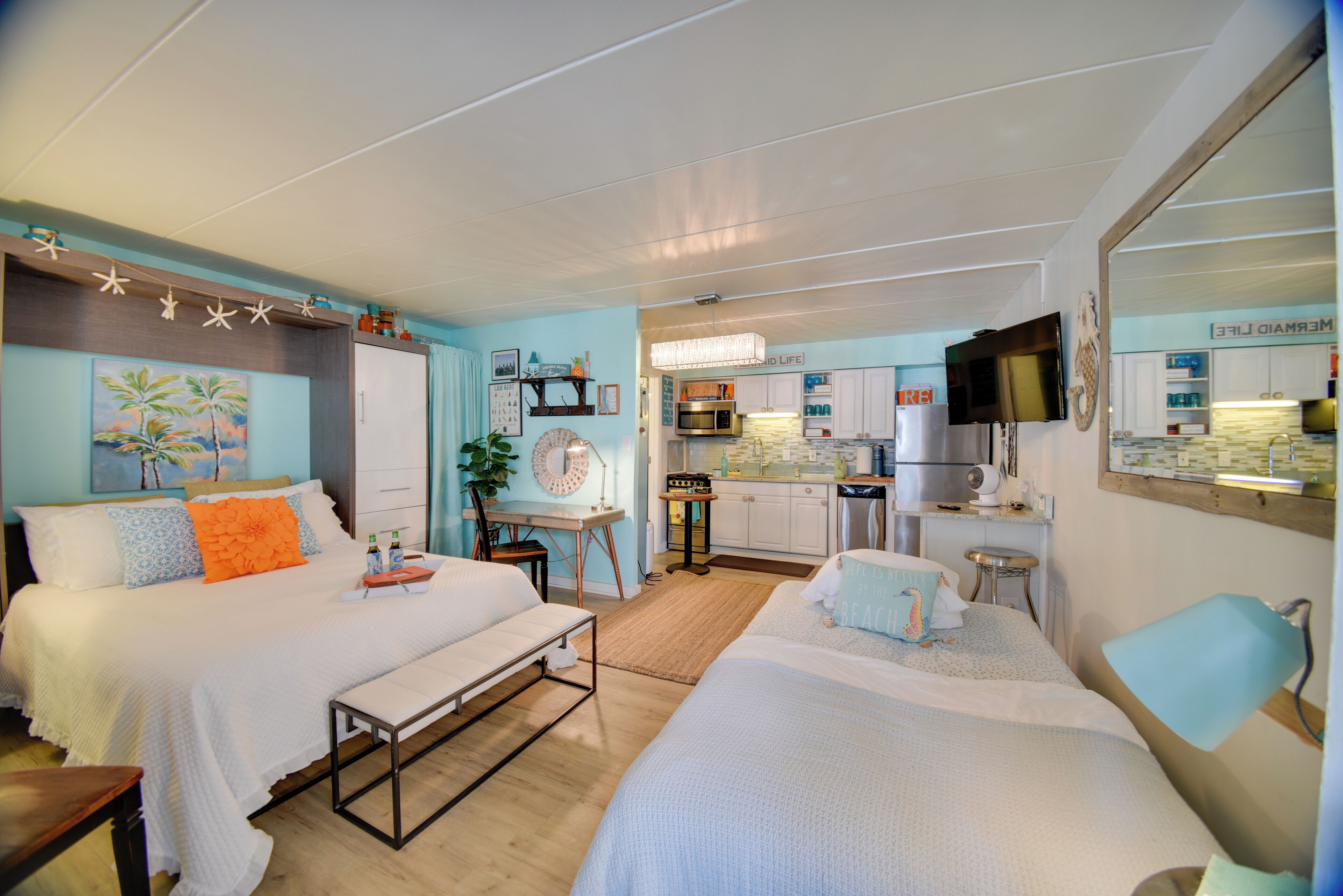 A hotel room with two beds, a kitchenette, a dining area, and a bathroom.