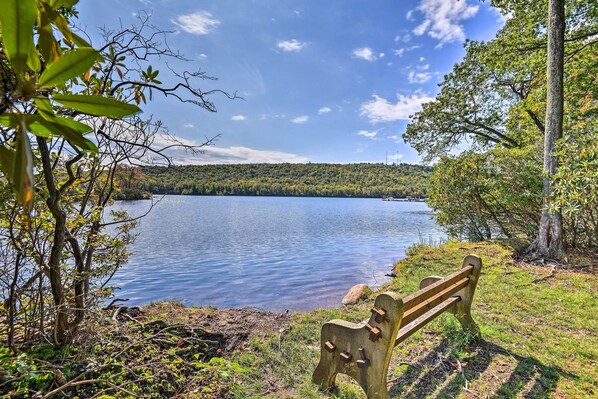 A wooden bench by a lake with trees and a clear sky. - 1 Mi to Big Boulder: Lakefront Unit w/ Pool Access (Lake Harmony)