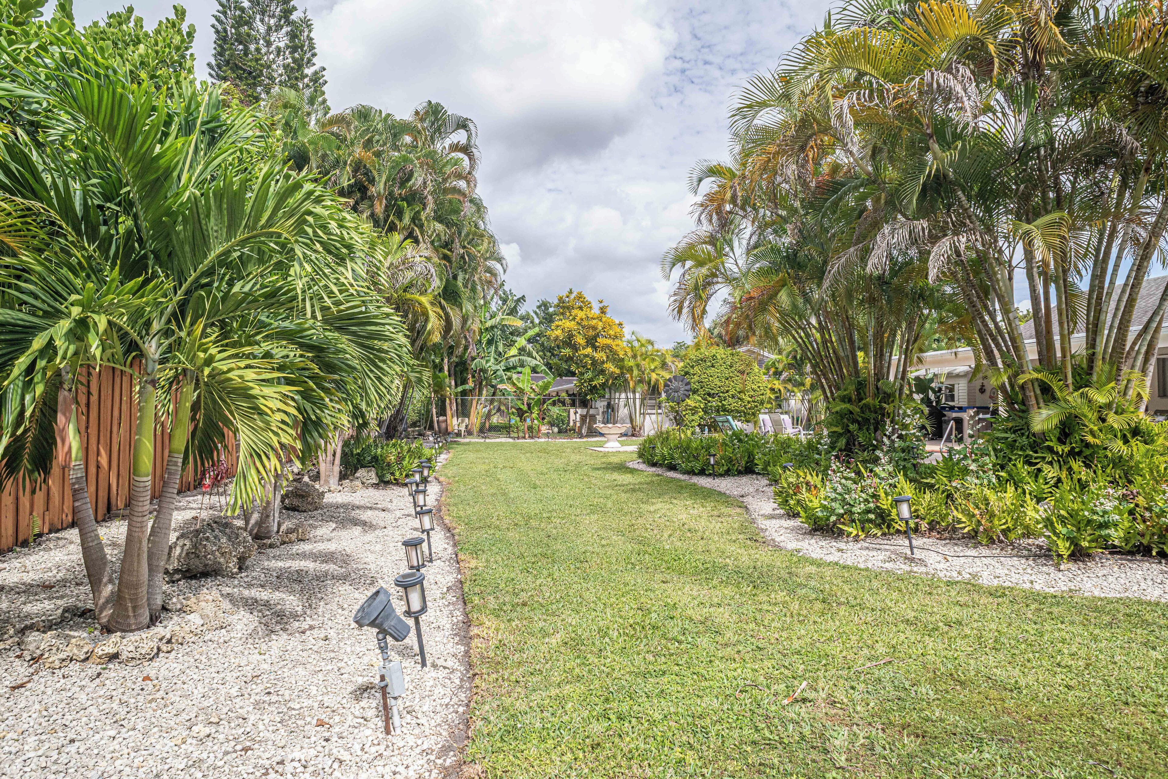 A well-maintained garden with a variety of tropical plants and a gravel path.