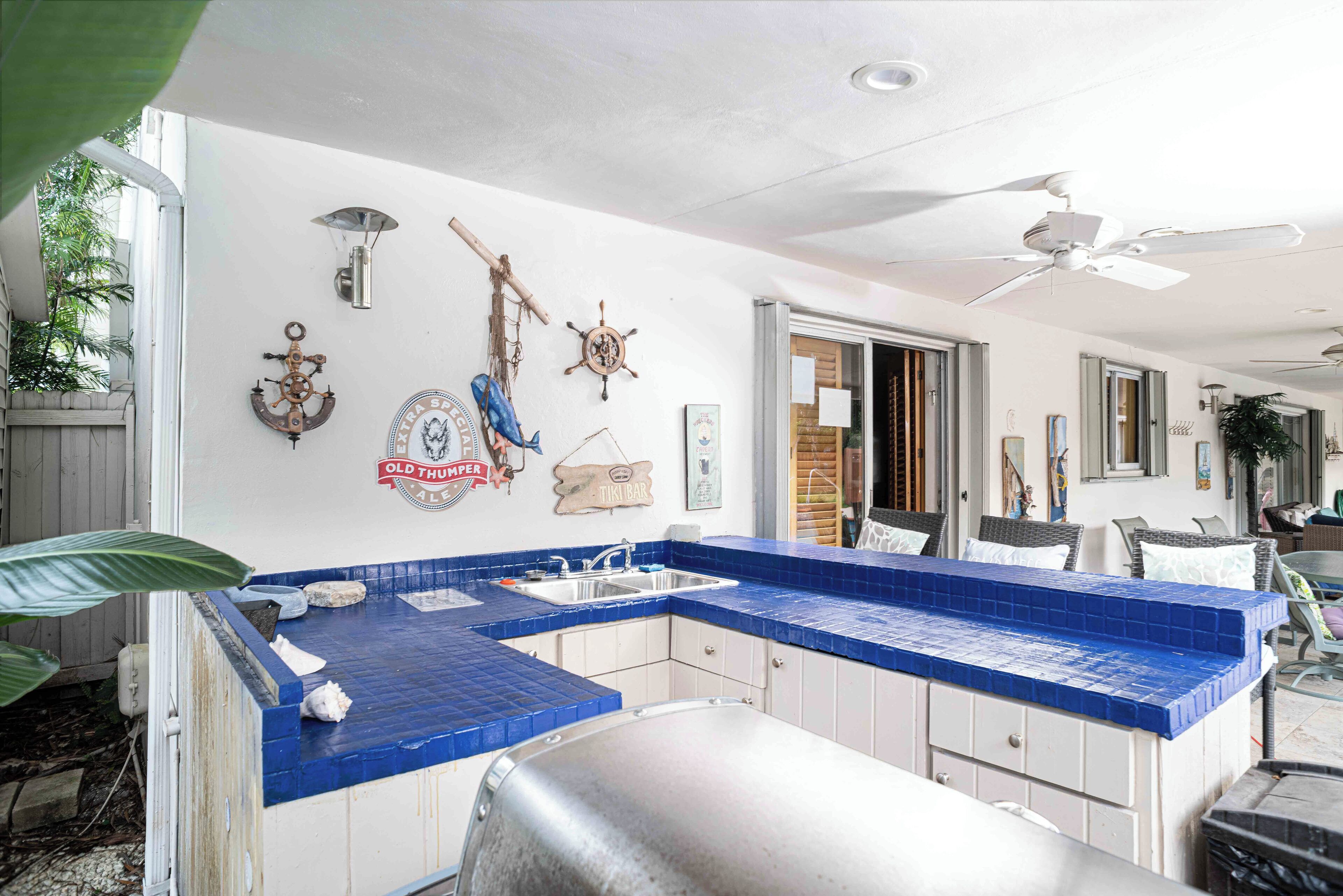 A kitchen with blue tiles, a stainless steel sink, and nautical-themed decorations.
