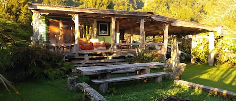 A rustic cabin with a porch, wooden benches, and a small garden area.