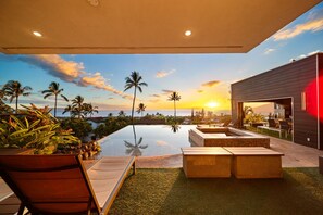 A modern outdoor pool area with lounge chairs and a view of the sunset over the ocean. - The Butterfly Home Maui (kihei)