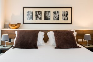 A hotel room with a bed, two brown pillows, a white pillow, a framed photo collage on the wall, a wooden bowl on a nightstand, and two lamps. - Renovated gorgeous villa in Florence. Walking distance to all sites. (Firenze)