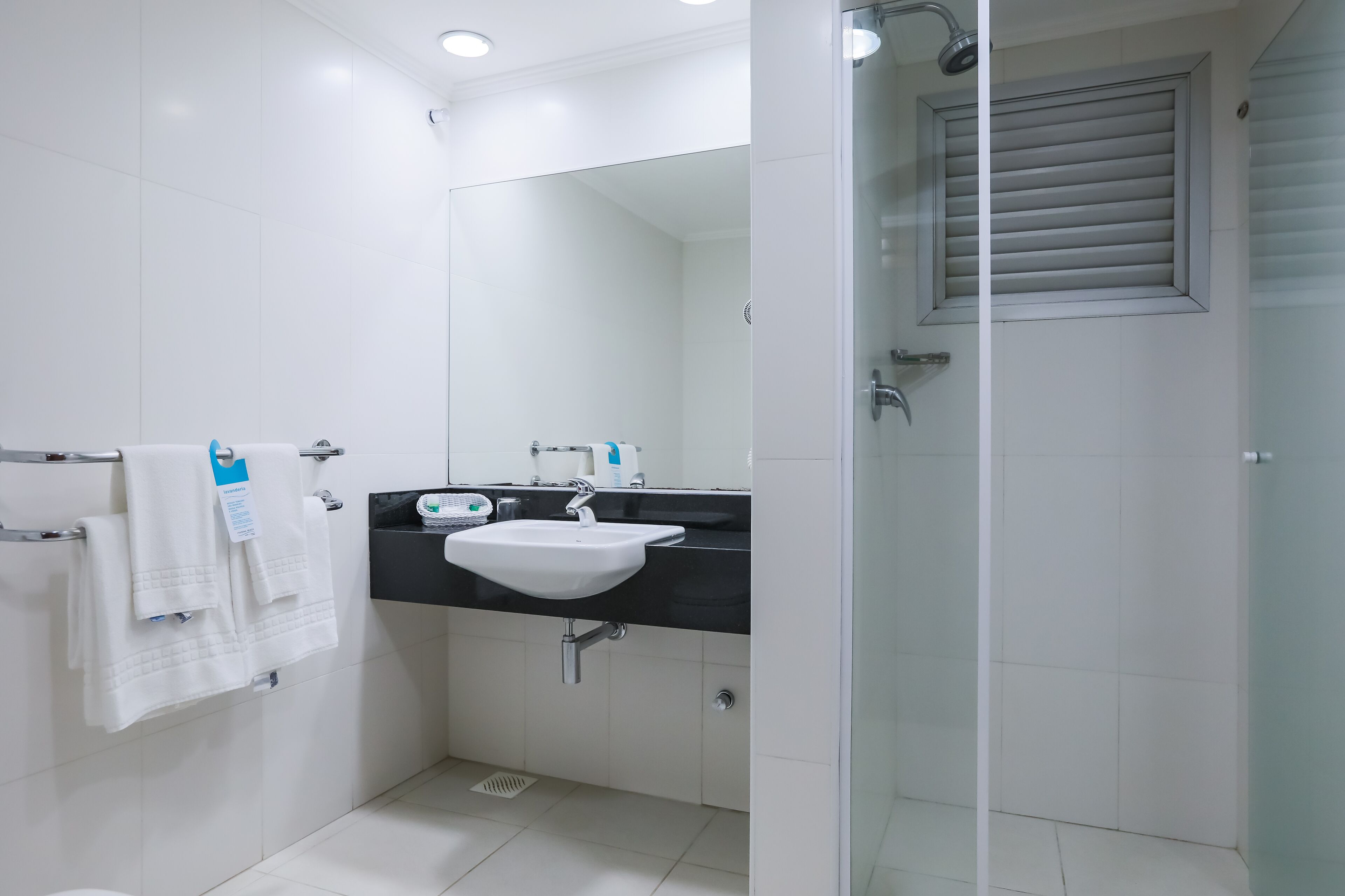 A modern bathroom with a glass-enclosed shower, a white sink, and a black countertop.