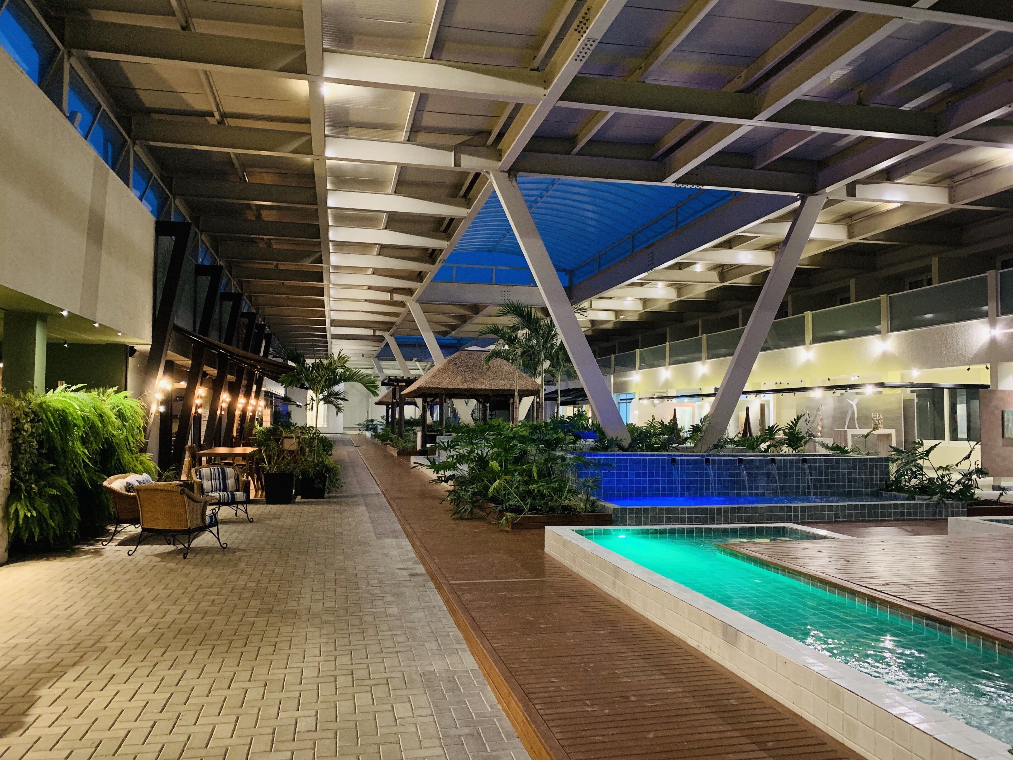 An indoor swimming pool area with a tiled floor, a wooden deck, and a blue ceiling.