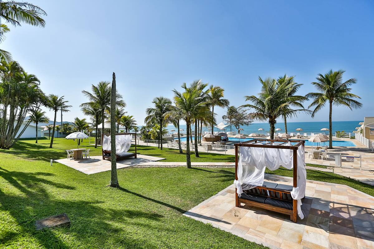 A luxurious outdoor area with a wooden canopy bed, palm trees, and a poolside lounge area.