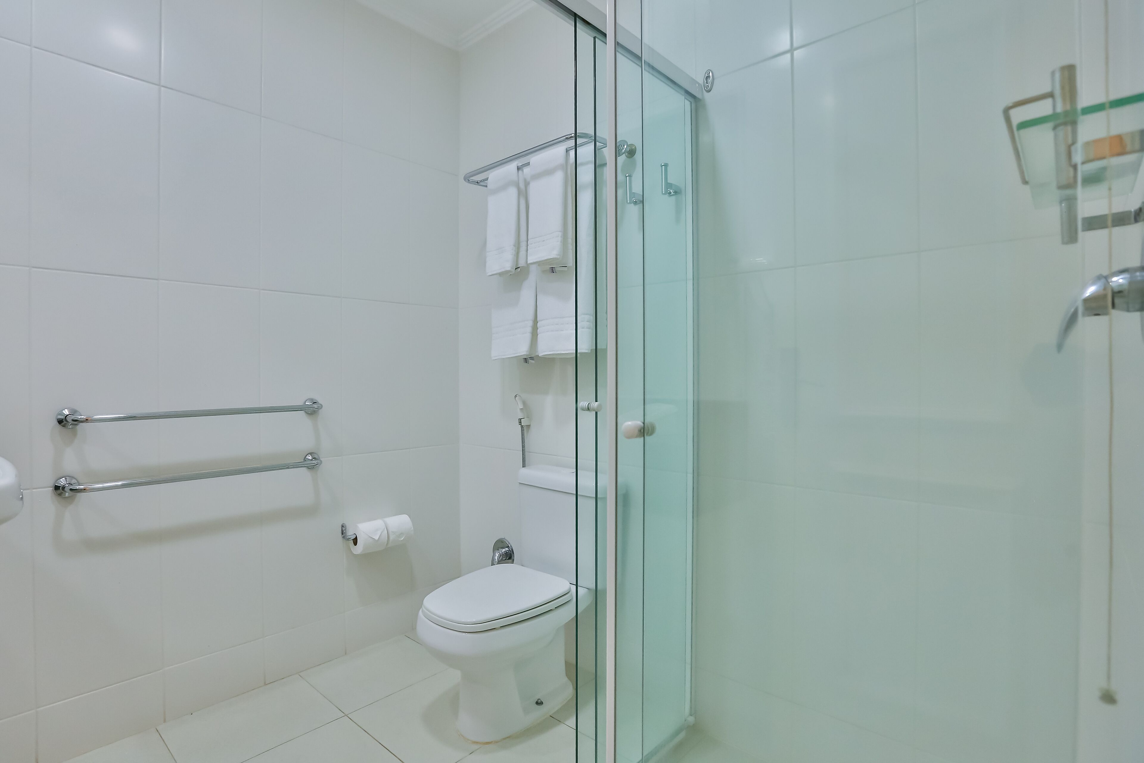 Un baño moderno con cabina de ducha de vidrio, inodoro y perchero para toallas.