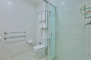 Un baño moderno con cabina de ducha de vidrio, inodoro y perchero para toallas.