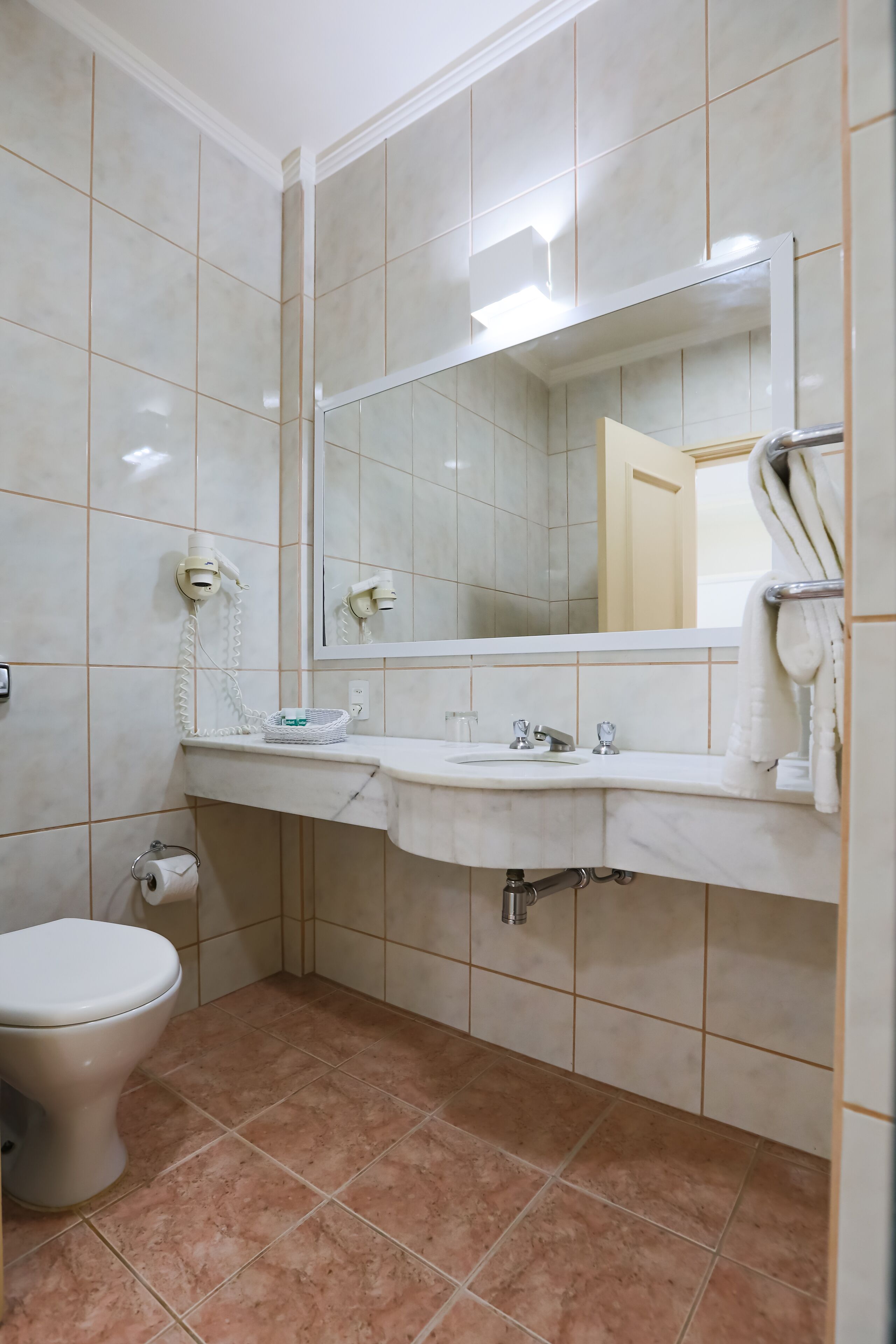 Un baño con inodoro, lavabo, espejo y toallero.