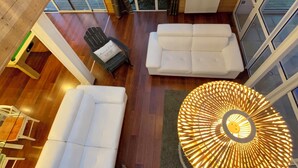 A modern interior with a wooden floor, white sofas, a black chair, and two hanging lamps. - House / Villa - Plouescat (Plouescat)