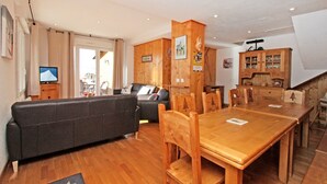 Una sala acogedora con una mesa de comedor de madera, un sofá y una televisión.