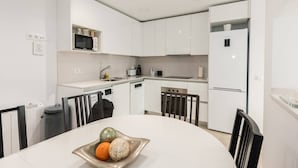A modern kitchen with white cabinetry, a microwave, a coffee maker, and a refrigerator. - MODERN APT WITH IDEAL LOCATION NEXT TO ATOCHA STATION (Madrid)