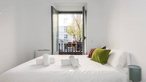 A hotel room with a bed, a nightstand, a lamp, and a view of the outside balcony. - MODERN APT WITH IDEAL LOCATION NEXT TO ATOCHA STATION (Madrid)