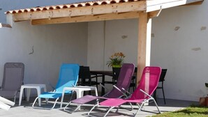 Un patio al aire libre con cuatro sillones, una mesa y una planta en maceta.