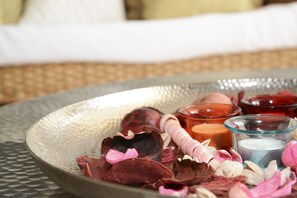A tray with dried flowers, candles, and a rolled-up towel on a textured surface.