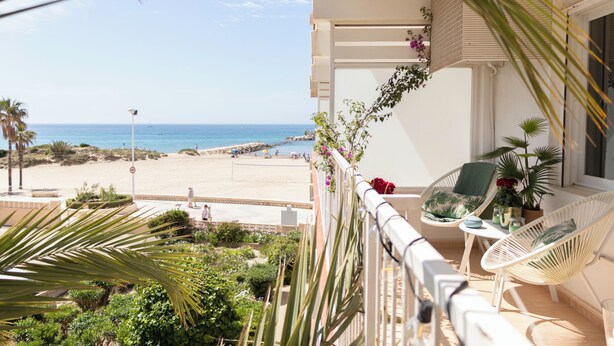 A balcony with a view of the beach, white wicker furniture, and potted plants. - Family-friendly apartment 20 m from Arenal Beach, Calpe (CALPE)
