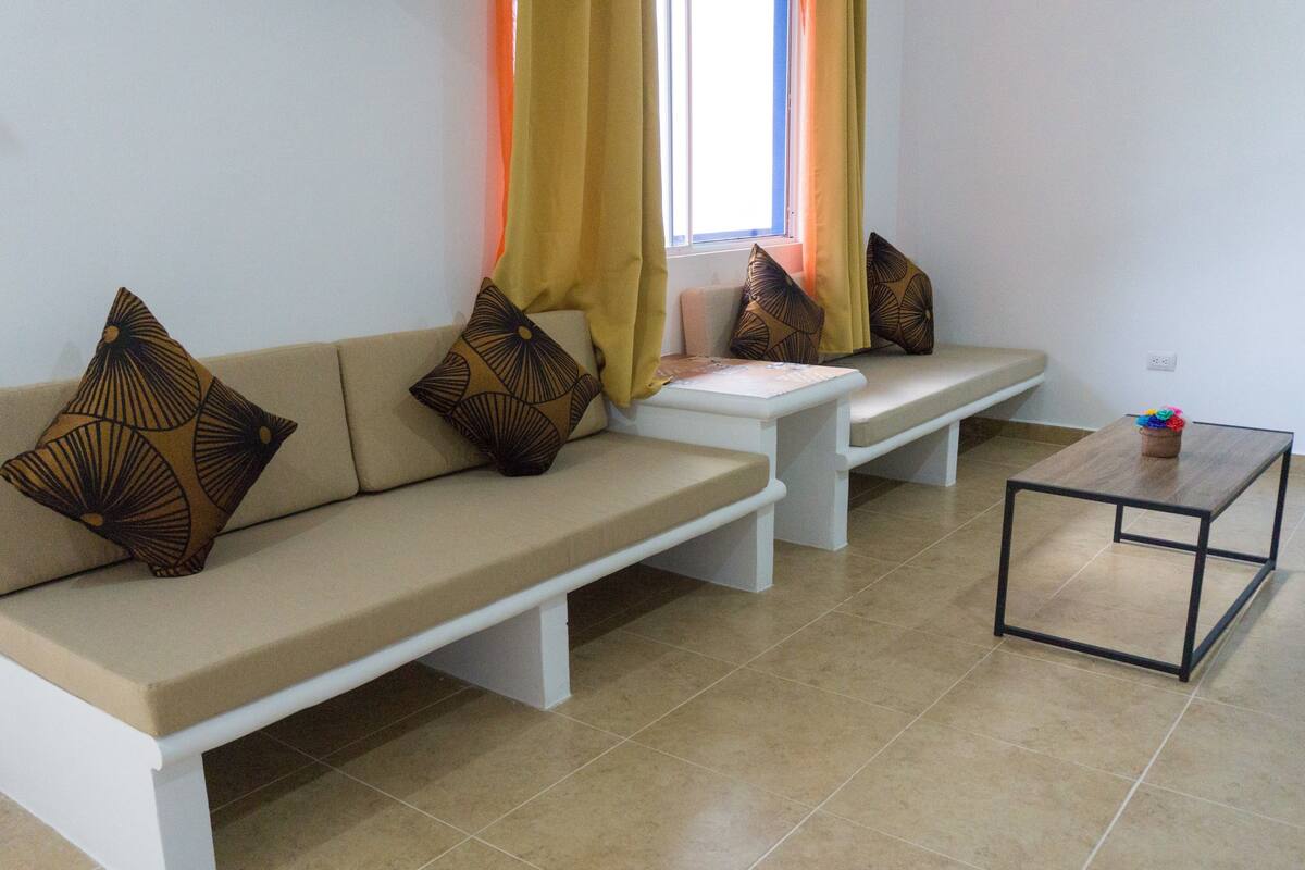 A living room with a sofa set, a coffee table, and a window with curtains.