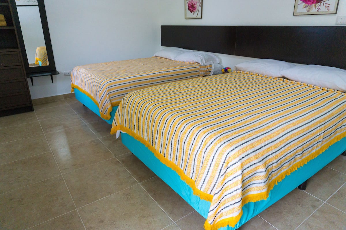 Two single beds with striped bedding, a dark headboard, and a tiled floor.