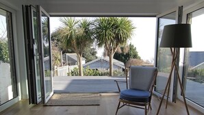 Ein Zimmer mit einer Schiebetür zu einem Balkon mit Palmen und Blick auf ein Haus.