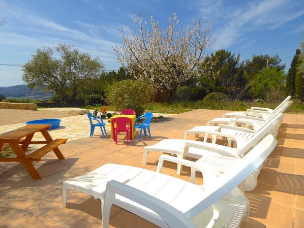 Terrasse mit Tischen und Stühlen, ein Picknicktisch und ein Baum in voller Blüte.