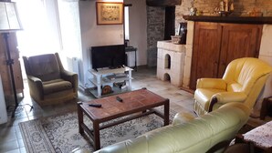 Una sala de estar con televisión, chimenea, sofá y sillón.
