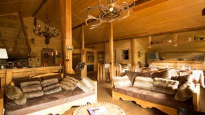 Un intérieur rustique en bois, avec deux canapés, un lustre et un coin repas.
