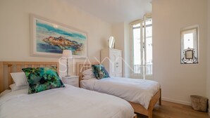 Ein Hotelzimmer mit zwei Betten, einem Bild an der Wand, einem Spiegel und einem Fenster.