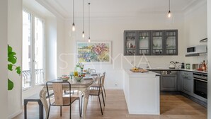 Eine moderne Küche mit Kochinsel, Pendelleuchten und einem großen Fenster für natürliches Licht.