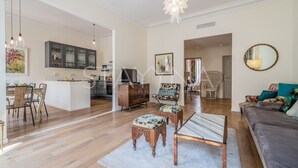 Ein großzügiges Wohnzimmer mit einer Couch, Poufs und einem Essbereich mit Tisch und Stühlen.