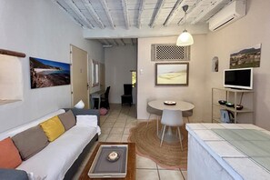 A compact living space with a sofa, a dining table with chairs, a TV, and artwork on the walls. - IN THE HEART OF THE HISTORIC DISTRICT: ALL THE CHARM OF BONIFACIO IN A SPACIOUS 2+1 STUDIO (Bonifacio)