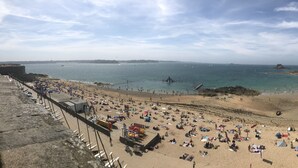 A beach with people sunbathing and swimming, a pier, and boats in the water. - Luxury 4* apartment with closed garage and pond view 50m from the Sillon beach (Saint-Malo)