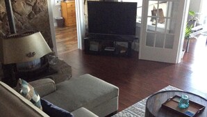 A living room with a sofa, a television, and a stone wall.