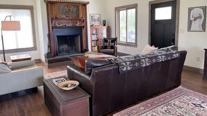 Ein Wohnzimmer mit Kamin, Ledersofa und Teppich.