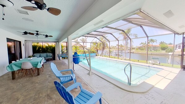 Un espacio al aire libre techado con piscina, mobiliario y vistas del paisaje circundante.